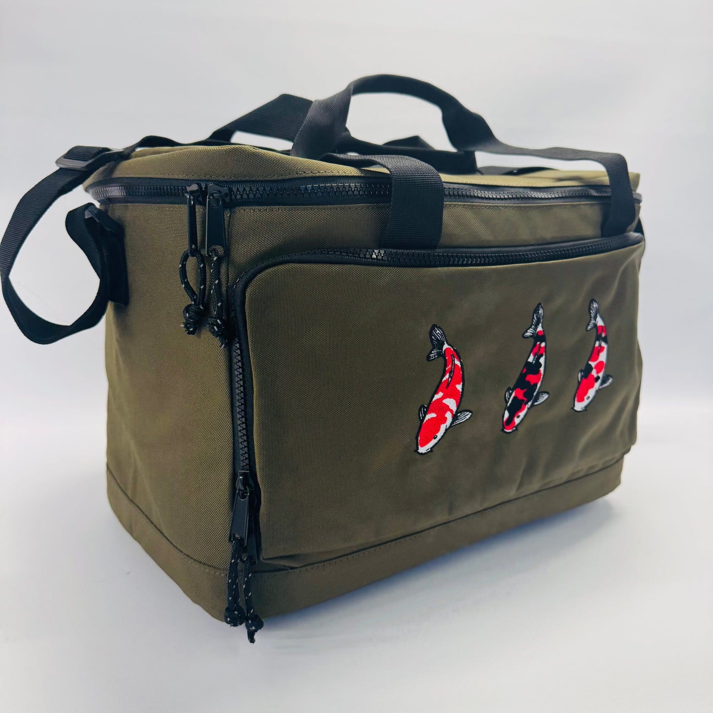 Green bag with embroidered koi fish designs on a white background